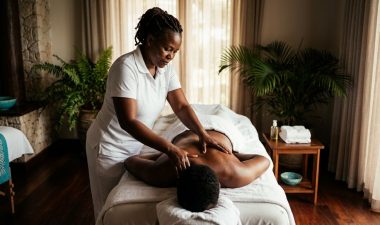 A massage therapist works on a client in a warmly lit, private spa room.